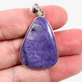 Purple Charoite tear drop pendant in sterling silver sitting in a hand