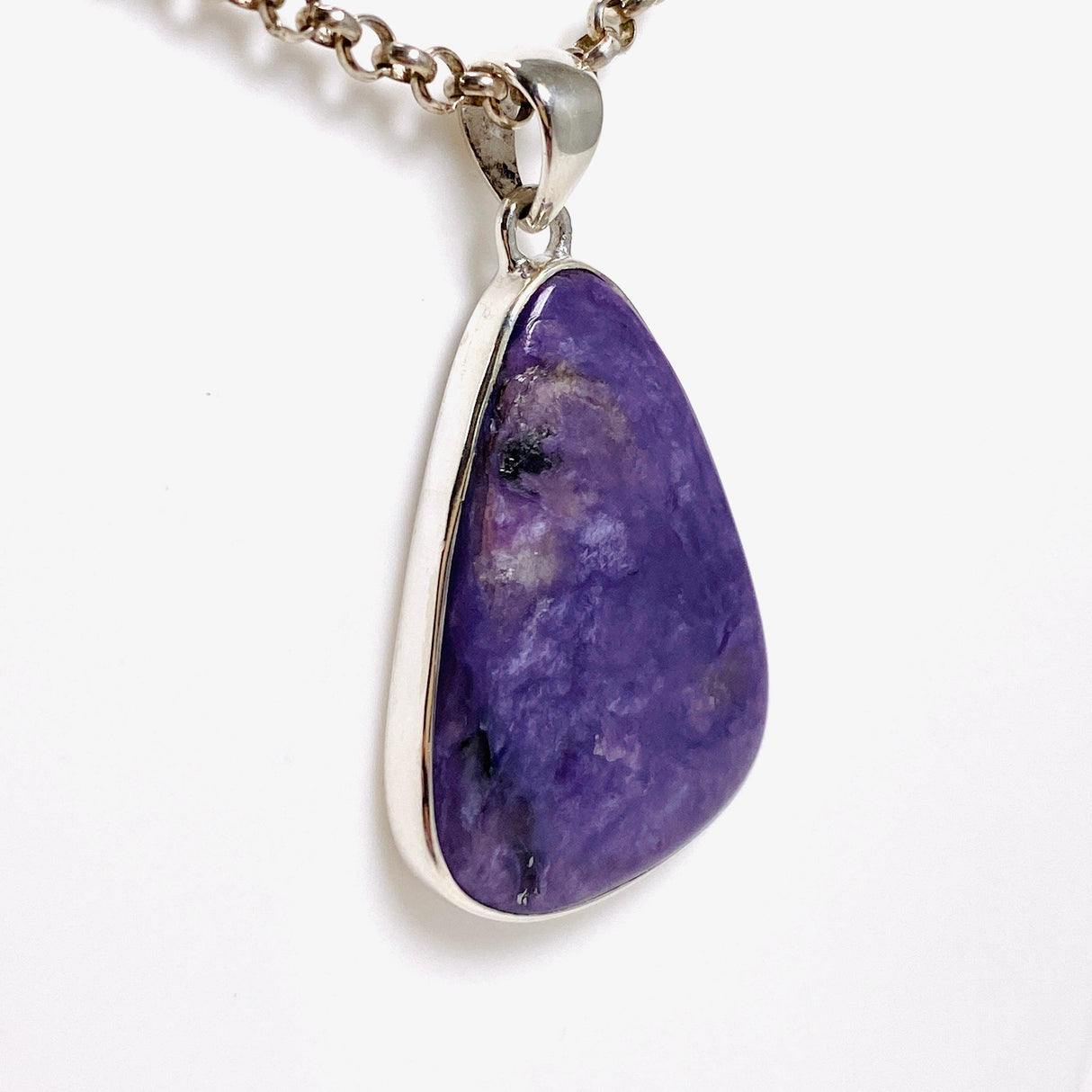 Purple Charoite tear drop pendant in sterling silver sitting on a chain