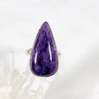 Purple Charoite tear drop ring in sterling silver sitting on a crystal cluster