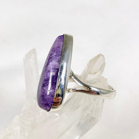 Purple Charoite tear drop ring in sterling silver sitting on a crystal cluster