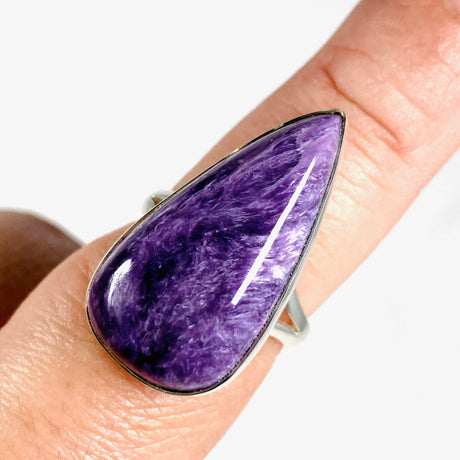 Purple Charoite tear drop ring in sterling silver sitting on a hand