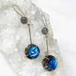 Labradorite and silver earrings with blue flower carving at the bottom with a silver stem going up to a small round labradoite gemstone with a fixed hook on a crystal cluster