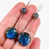 Labradorite and silver earrings with blue flower carving at the bottom with a silver stem going up to a small round labradoite gemstone with a fixed hook in the hand