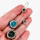 Labradorite and silver earrings with blue flower carving at the bottom with a silver stem going up to a small round labradoite gemstone with a fixed hook in the hand showing back of the earrings