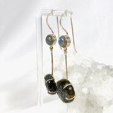 Labradorite and silver earrings with blue flower carving at the bottom with a silver stem going up to a small round labradoite gemstone with a fixed hook hangning from a stand