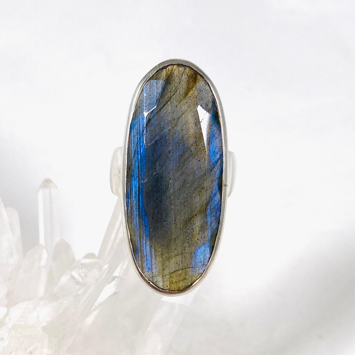 Blue iridescent Labradorite faceted gemstone ring set in silver on a clear quartz crystal