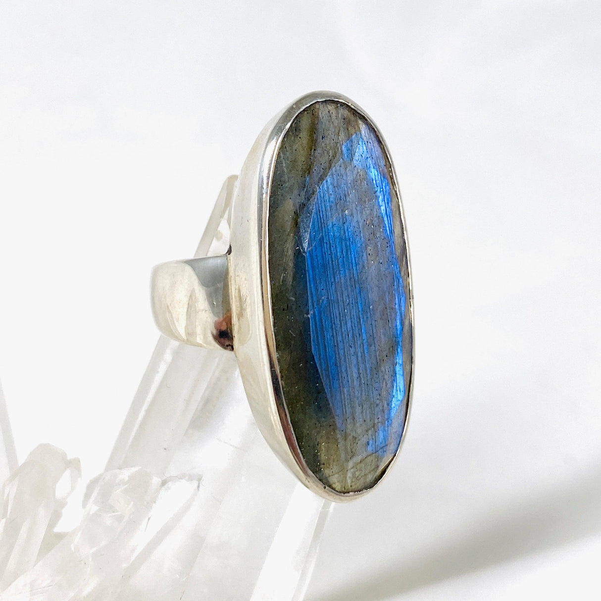 Blue iridescent Labradorite faceted gemstone ring set in silver on a clear quartz crystal