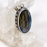 Blue iridescent Labradorite faceted gemstone pendant set in silver on a clear quartz crystal