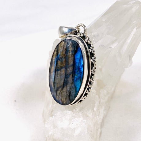 Blue iridescent Labradorite faceted gemstone pendant set in silver on a clear quartz crystal