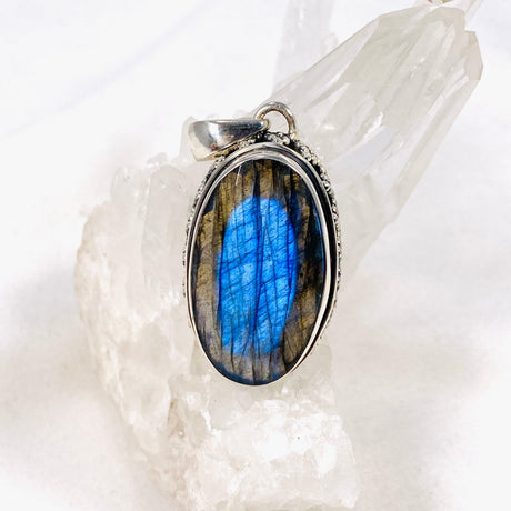 Blue iridescent Labradorite faceted gemstone pendant set in silver on a clear quartz crystal