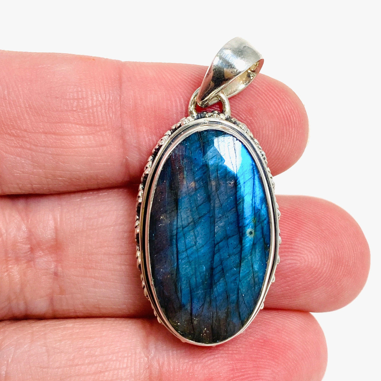 Blue iridescent Labradorite faceted gemstone pendant set in silver on a hand