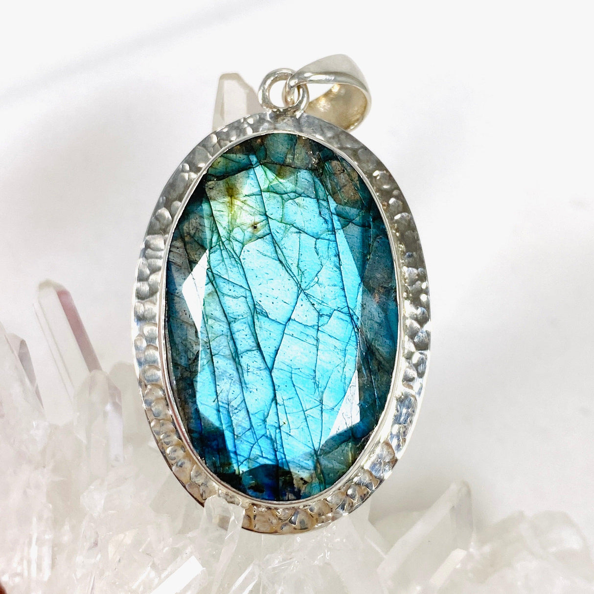 Blue iridescent Labradorite faceted gemstone and silver pendant on a clear quartz crystal