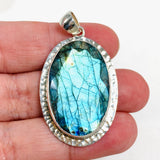 Blue iridescent Labradorite faceted gemstone and silver pendant in hand