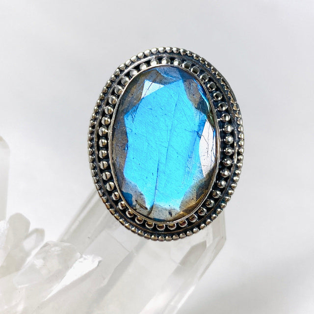 Blue iridescent Labradorite faceted gemstone ring set in silver on a clear quartz crystal