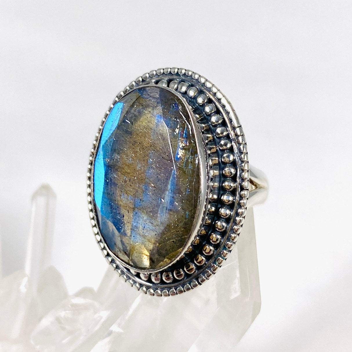 Blue iridescent Labradorite faceted gemstone ring set in silver on a clear quartz crystal