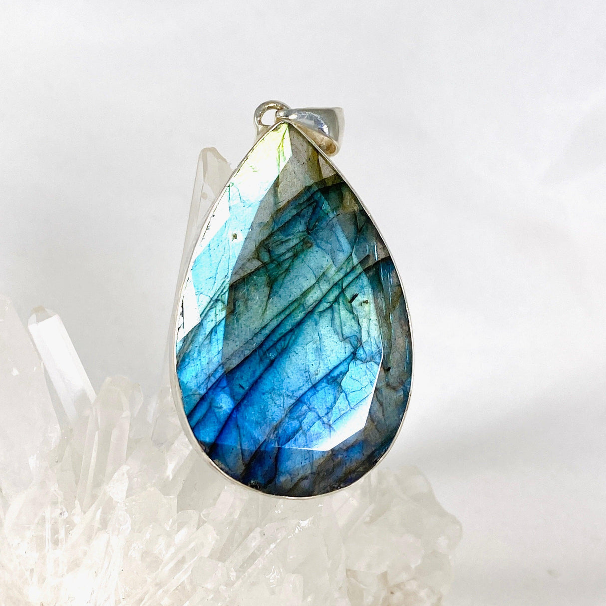 Blue iridescent Labradorite faceted gemstone pendant set in silver on a clear quartz crystal