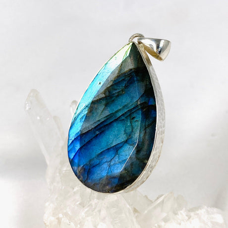 Blue iridescent Labradorite faceted gemstone pendant set in silver on a clear quartz crystal