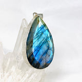 Blue iridescent Labradorite faceted gemstone pendant set in silver on a clear quartz crystal