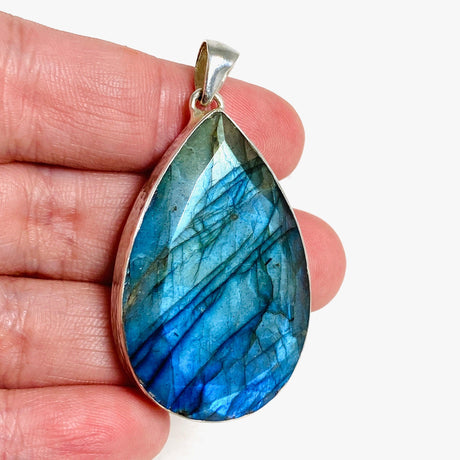 Blue iridescent Labradorite faceted gemstone pendant set in silver on a hand