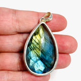 Blue iridescent Labradorite faceted gemstone pendant set in silver showing the back of the pendant in the hand