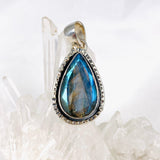 Blue iridescent Labradorite faceted gemstone pendant set in silver on a clear quartz crystal