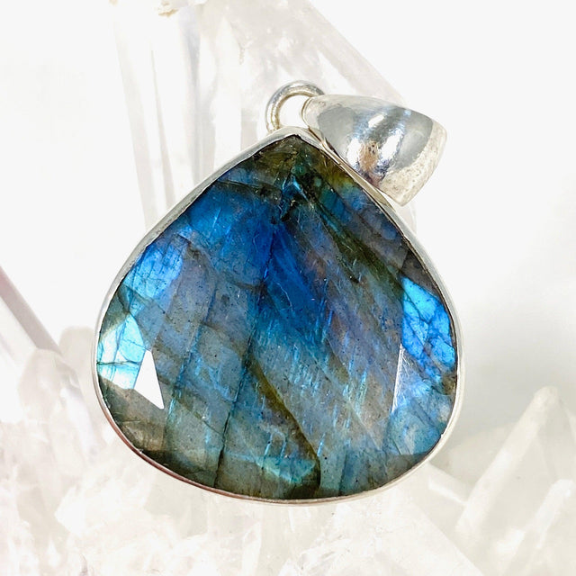 Blue iridescent Labradorite faceted gemstone and silver pendant on a clear quartz crystal