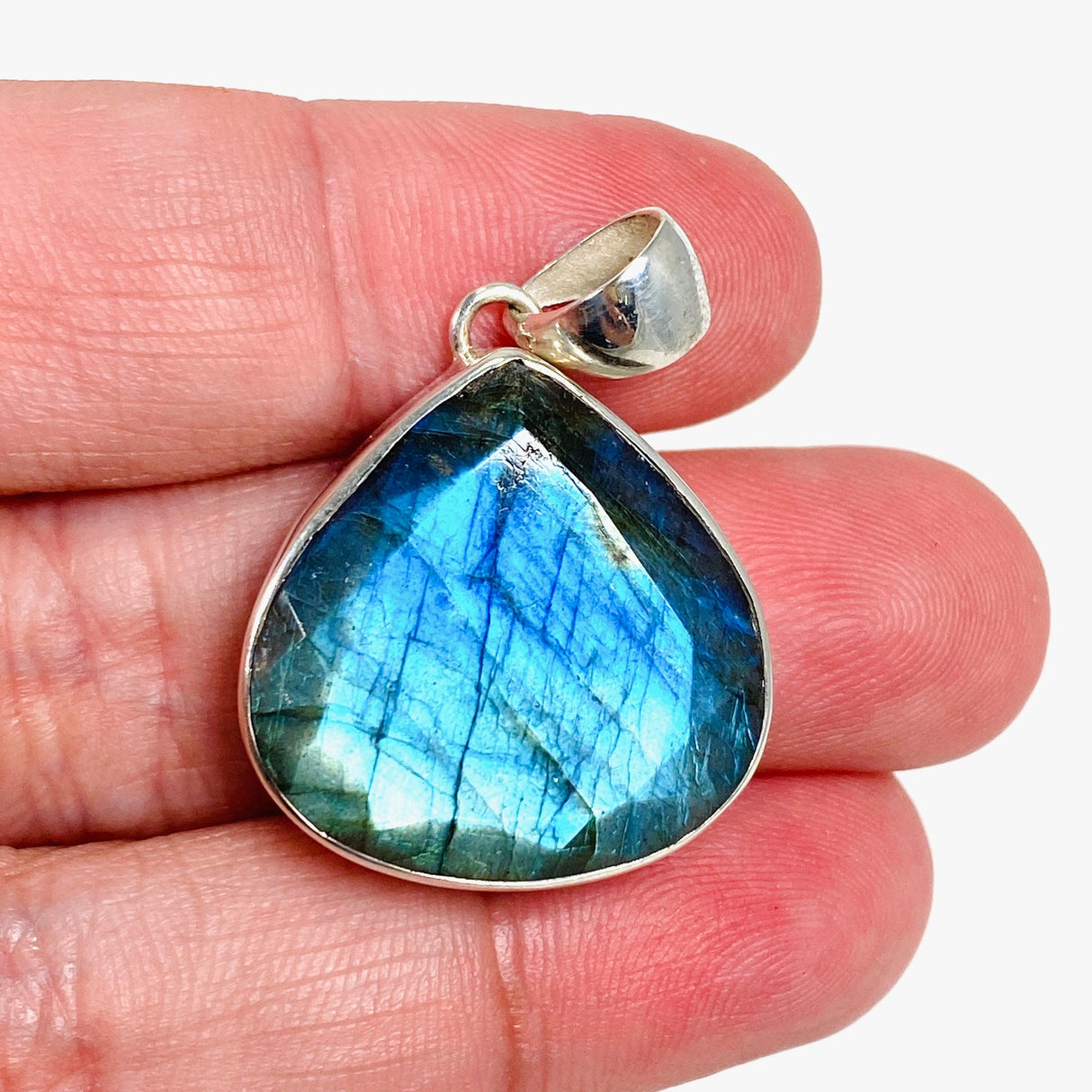 Blue iridescent Labradorite faceted gemstone and silver pendant on a hand