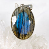 Blue iridescent Labradorite faceted gemstone and silver pendant on a clear quartz crystal