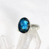 Blue iridescent Labradorite faceted gemstone and silver ring on a clear quartz crystal