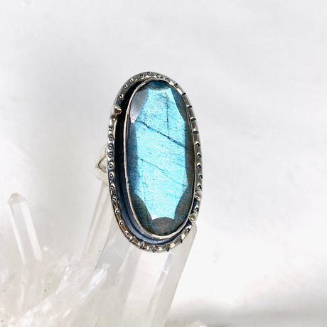 Blue iridescent Labradorite faceted gemstone ring set in silver on a clear quartz crystal