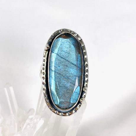 Blue iridescent Labradorite faceted gemstone ring set in silver on a clear quartz crystal