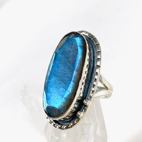 Blue iridescent Labradorite faceted gemstone ring set in silver on a clear quartz crystal