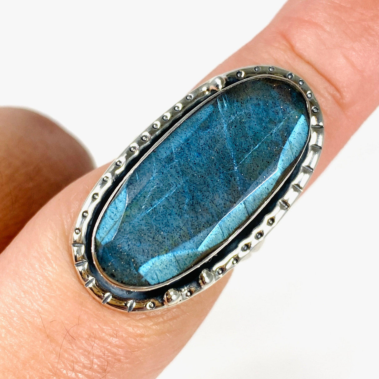 Blue iridescent Labradorite faceted gemstone ring set in silver on a finger