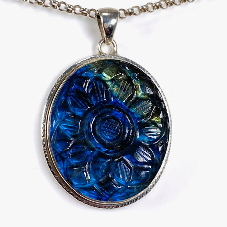 Oval shaped blue and gold flash labradorite flower carving pendant set in silver shown on a silver belcher chain