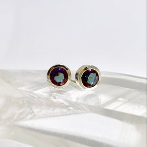 Multicolored gemstone stud earrings on a white surface