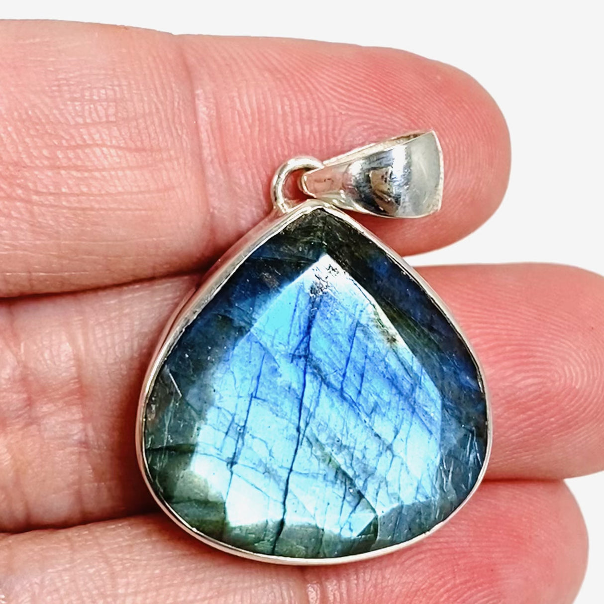 Blue iridescent Labradorite faceted gemstone and silver pendant in hand on live video