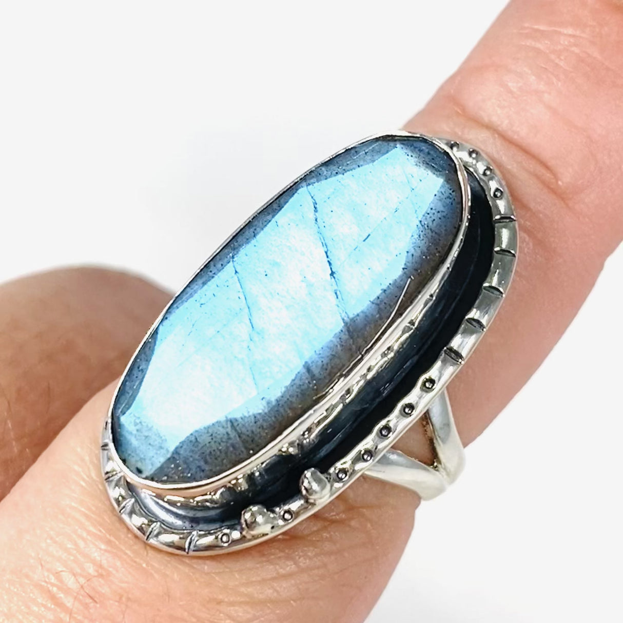 Blue iridescent Labradorite faceted gemstone ring set in silver on a finger