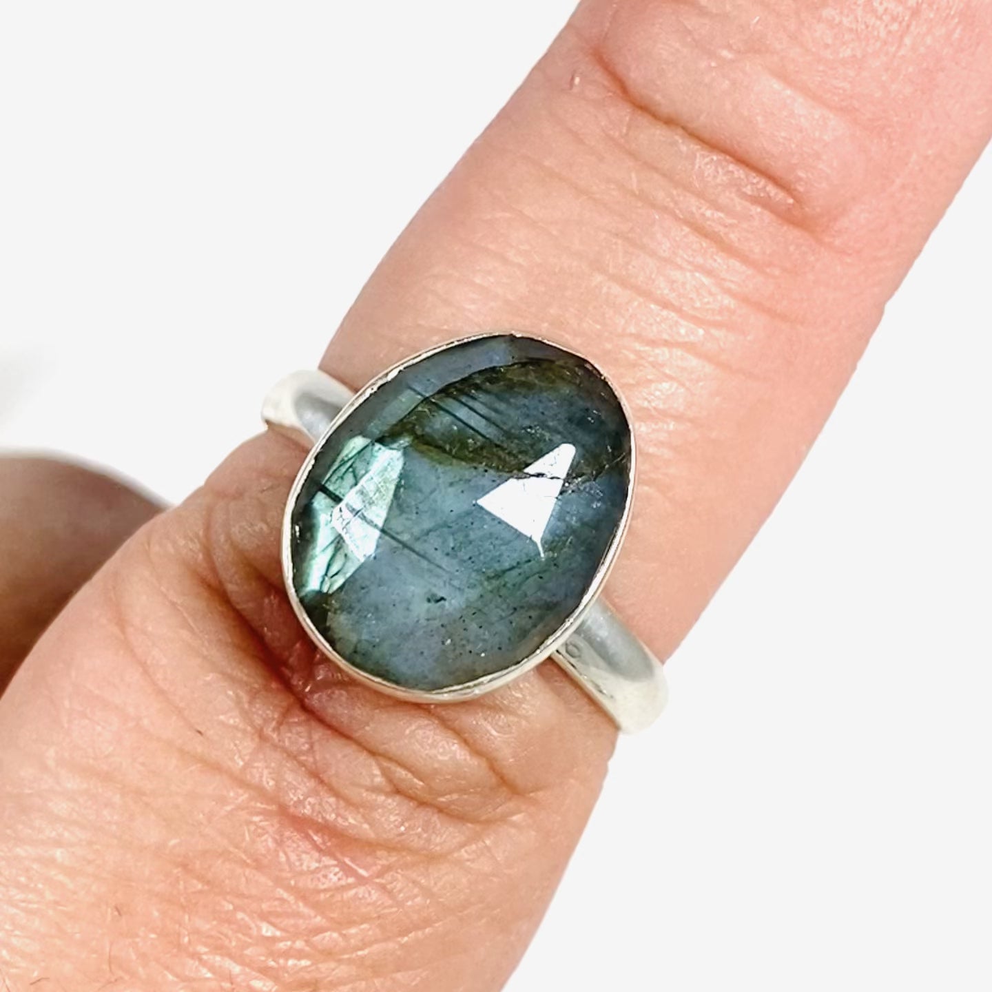 Blue iridescent Labradorite faceted gemstone and silver ring on a finger
